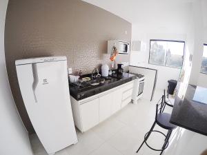 a kitchen with a white refrigerator and a sink at Condomínio Vista Nobre in Varginha +10 photos