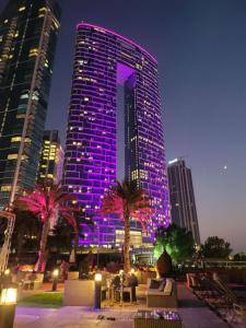 a tall building with purple lights in a city at The Star @ Address Beach Residence in Dubai