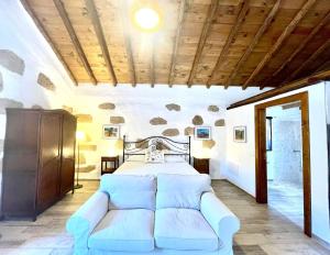 a bedroom with a white bed and a couch at Rural house with private pool, BBQ, and views of the Atlantic Ocean in Tenerife South in San Miguel de Abona