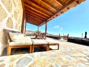a porch with a couch and chairs on the beach at Rural house with private pool, BBQ, and views of the Atlantic Ocean in Tenerife South in San Miguel de Abona