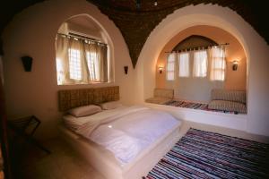 a bedroom with a bed in a room with two windows at Tzila Bahariya in Az Zaytūn