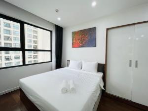 um quarto com uma cama branca com dois sapatos brancos em VNRooms - 2BR Vinhomes D'Capitale/ LAKE VIEW/ 23Fl em Hanói