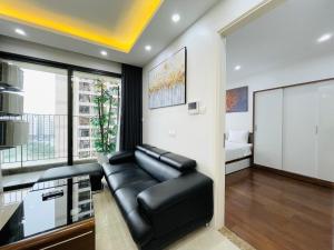 uma sala de estar com um sofá de couro preto e uma cama em VNRooms - 2BR Vinhomes D'Capitale/ LAKE VIEW/ 23Fl em Hanói