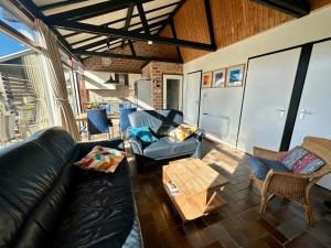 a living room with a leather couch and chairs at Boerenslag 42 in Sint Maartensvlotbrug