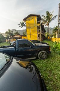 a black truck parked in front of a yellow building at Duplex Sol in Maresias