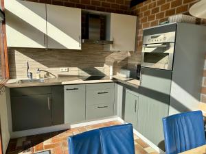 a kitchen with white cabinets and blue chairs at Boerenslag 42 in Sint Maartensvlotbrug