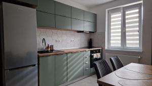 a kitchen with green cabinets and a table with chairs at CENTRAL 6 in Topliţa