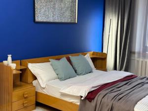 a bedroom with a bed with a blue wall at Квартира на Атакенте у Выставки in Almaty