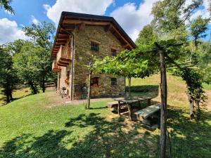 une maison en pierre avec une table de pique-nique devant elle dans l'établissement Agriturismo l'Arbo, à Andorno Micca