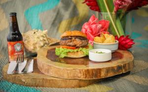 a hamburger and chips on a wooden plate with a bottle of beer at La Brisa Tranquila in Guachaca