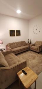 sala de estar con sofá, mesa y reloj en فيلا فيوتشر en Al Fayşalīyah