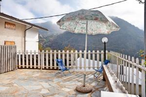 un patio con 2 sillas azules y una sombrilla en Casa paradiso di montagna, en Roccaforte Mondovì
