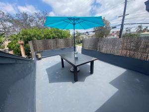 a table with a blue umbrella sitting on a patio at Lovely 2BR Home with Fireplace and Patio in Culver in Los Angeles
