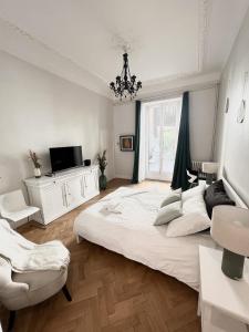 a white bedroom with a large bed and a chandelier at Sublime Appartement de 105 m2 dans l'hyper centre avec Terrasse et parking à 5 min de la mer in Nice