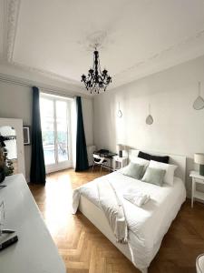 a bedroom with a large white bed and a chandelier at Sublime Appartement de 105 m2 dans l'hyper centre avec Terrasse et parking à 5 min de la mer in Nice