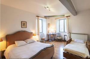 1 dormitorio con 2 camas y mesa en Demeure de 15 chambres avec piscine privee jardin clos et wifi a Satillieu en Satillieu