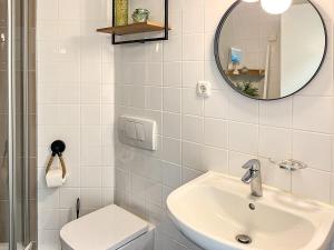 Un baño blanco con lavabo y espejo. en Haus am Teich Wohnung 19, en Boltenhagen 17 fotos más