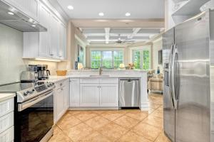 a kitchen with white cabinets and a stainless steel refrigerator at The Key Canal - 455 in Siesta Key