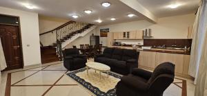 a living room with couches and a table and a kitchen at Diplomatic Short Stay in Gigiri in Nairobi