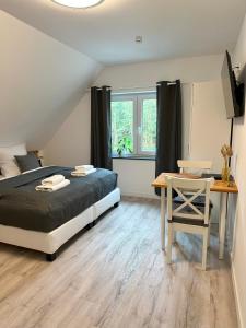 a bedroom with a bed and a table and a window at Lagom - Apartments an der Barclays Arena in Hamburg