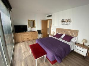een slaapkamer met een paars bed en een televisie bij Altos Golf Bahía Benidorm in Finestrat