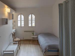 ein Schlafzimmer mit einem Bett, einem Tisch und zwei Fenstern in der Unterkunft Gîte d'étape la P'tite Graine in Auvillar