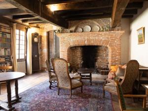 ein Wohnzimmer mit einem gemauerten Kamin mit Stühlen und einem Tisch in der Unterkunft Gîte d'étape la P'tite Graine in Auvillar