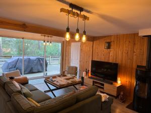 a living room with a couch and a flat screen tv at Chalet du bonheur - La Jenny naturist area in Le Porge