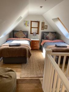 um quarto no sótão com 2 camas e uma escada em Eakie House Apartments - Kinlochleven em Kinlochleven