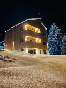 a building in the snow at night at NORDIC Apartamente Păltiniș in Păltiniş