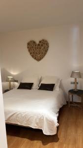 Un dormitorio con una cama blanca con un corazón en la pared en Appartement au coeur d'Ordino en Ordino