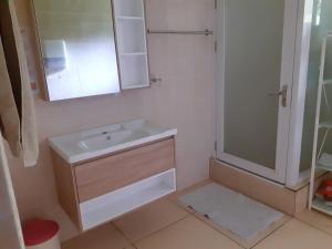 uma casa de banho branca com um lavatório e um chuveiro em Gigi's Self Catering Apartment em Port Glaud