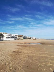 una playa de arena con casas en el fondo y un cielo azul en Encanto Mediterráneo with Airco, en Oliva