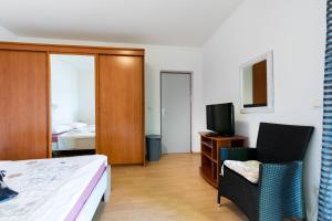 a bedroom with a bed and two chairs and a television at Apartments Sabina in Supetarska Draga