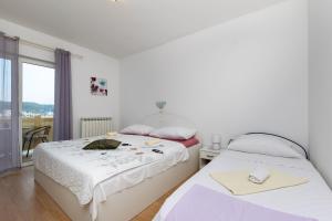 two beds in a room with a window at Apartments Sabina in Supetarska Draga