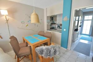 ein Wohnzimmer mit einem Tisch und Stühlen sowie eine Küche in der Unterkunft Haus Möwenstr 9, Haus 6 in Grömitz
