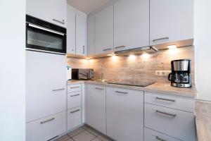eine weiße Küche mit weißen Schränken und Geräten in der Unterkunft Kaiserhof Whg 664 in Grömitz