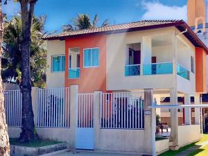 a house with a white fence and palm trees at Mar, Piscina, Diversão: Sua Casa de Praia - Meaipe in Guarapari