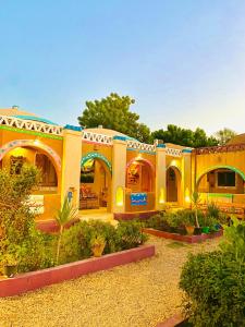 a yellow building with a garden in front of it at Kabara Nubian House in Abu Simbel
