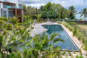 a swimming pool with palm trees in front of a house at Prestigious waterfront apartment with huge pool! in Pointe aux Piments