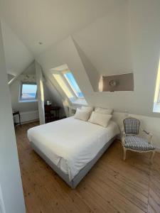 um quarto com uma cama branca e uma cadeira em Villa Sainte-Anne - Ploemeur em Ploemeur