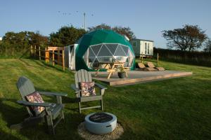 ein Zelt mit Stühlen und einem Tisch auf einem Feld in der Unterkunft Sunset Ridge - Luxury Geodesic Dome set in the beautiful countryside in Porkellis