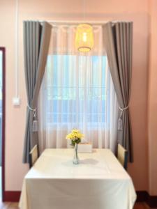 a vase of flowers on a table in front of a window at PP Pool Villa Maesalong Chiangrai in Mae Salong Nai