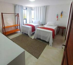 een kamer met 2 bedden en een raam bij Casa Milagres 03 suítes - 300m da Praia, 6 pessoas in Pôrto de Pedras