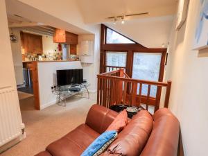 ein Wohnzimmer mit einem Ledersofa und einer Küche in der Unterkunft Wood Cottage in Kendal