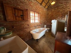 bagno con vasca bianca e parete in mattoni di Schoemanshof a Potchefstroom
