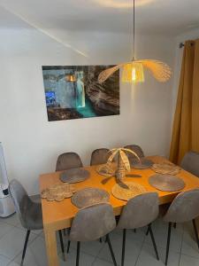 une table à manger avec des chaises et un tableau mural dans l'établissement Appartement proche gare TGV, à Nîmes