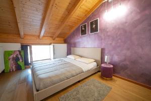 a bedroom with a bed and a purple wall at LE MUSE Comano Terme Holiday 2, primo piano in Comano Terme