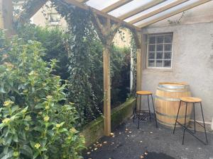 pergola z dwoma stołkami i beczką w ogrodzie w obiekcie Love Room Cocooning & Spa w mieście Épinal