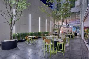 un restaurante con mesas, sillas y árboles en City Express Plus by Marriott Reforma El Ángel, en Ciudad de México